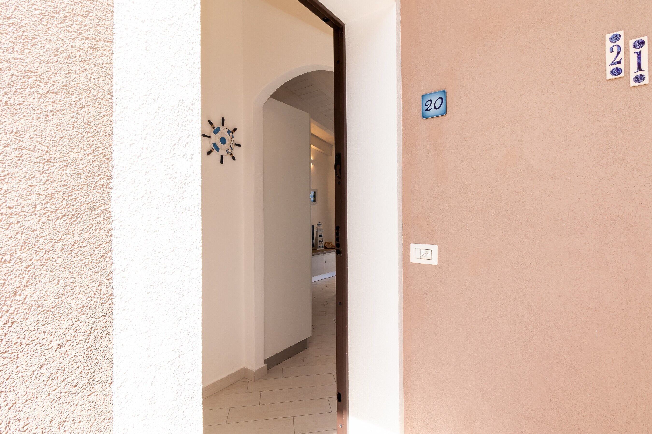 A hallway leading to a kitchen with a tiled floor and a door marked with the number 20.