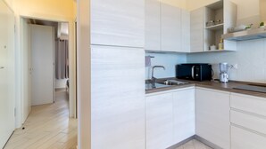 A modern kitchen with white cabinetry, a microwave, a blender, and a sink. - Apartment "Vista Bocche di Bonifacio" with Outdoor Pool (Isola Rossa)