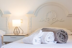 A neatly made bed with rolled towels, a bedside lamp, and a decorative wall. - Holiday Home "Tomymar" with Pool, Wi-Fi, Garden, and Terrace (Cala Ratjada)