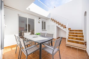 Une terrasse avec une table et des chaises, un escalier et une vue sur le ciel.