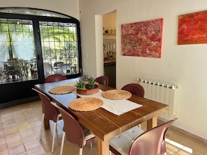 Un coin repas avec une table en bois, des sets de table en fibres tressées et des chaises rouges.