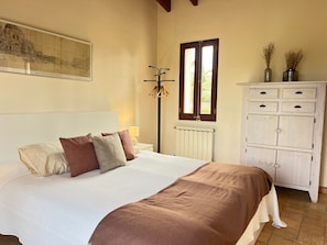 Une chambre à coucher comprenant un lit, un radiateur, une fenêtre, une armoire et un tableau accroché au mur.