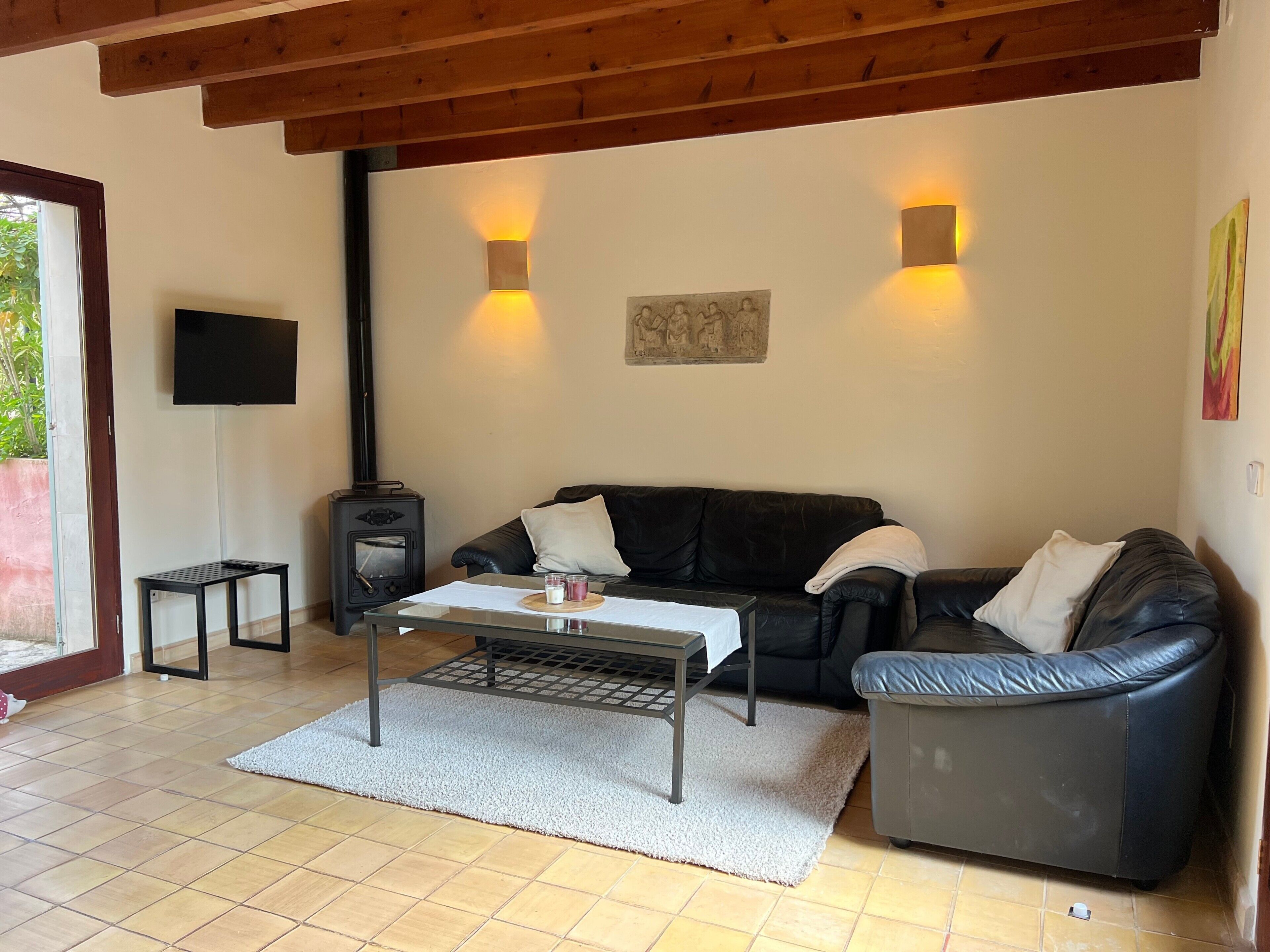 Un salon avec un canapé en cuir noir, une table basse, une cheminée et deux lampes fixées au mur.
