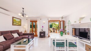 Una sala de estar con sofá, mesa de centro, televisor y comedor.