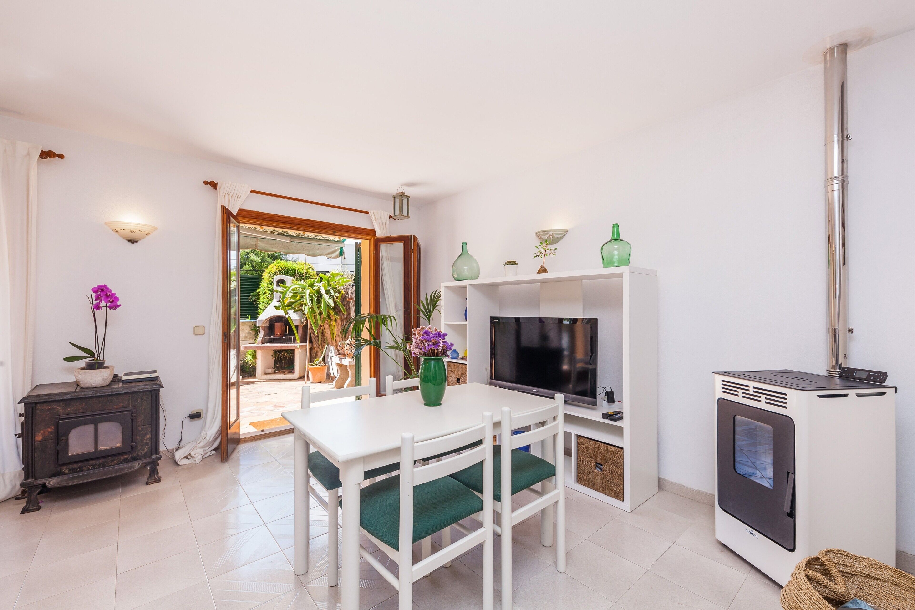 Eine moderne Küche mit Esstisch, Stühlen, einem Fernseher, einem Herd und Blick auf den Garten.