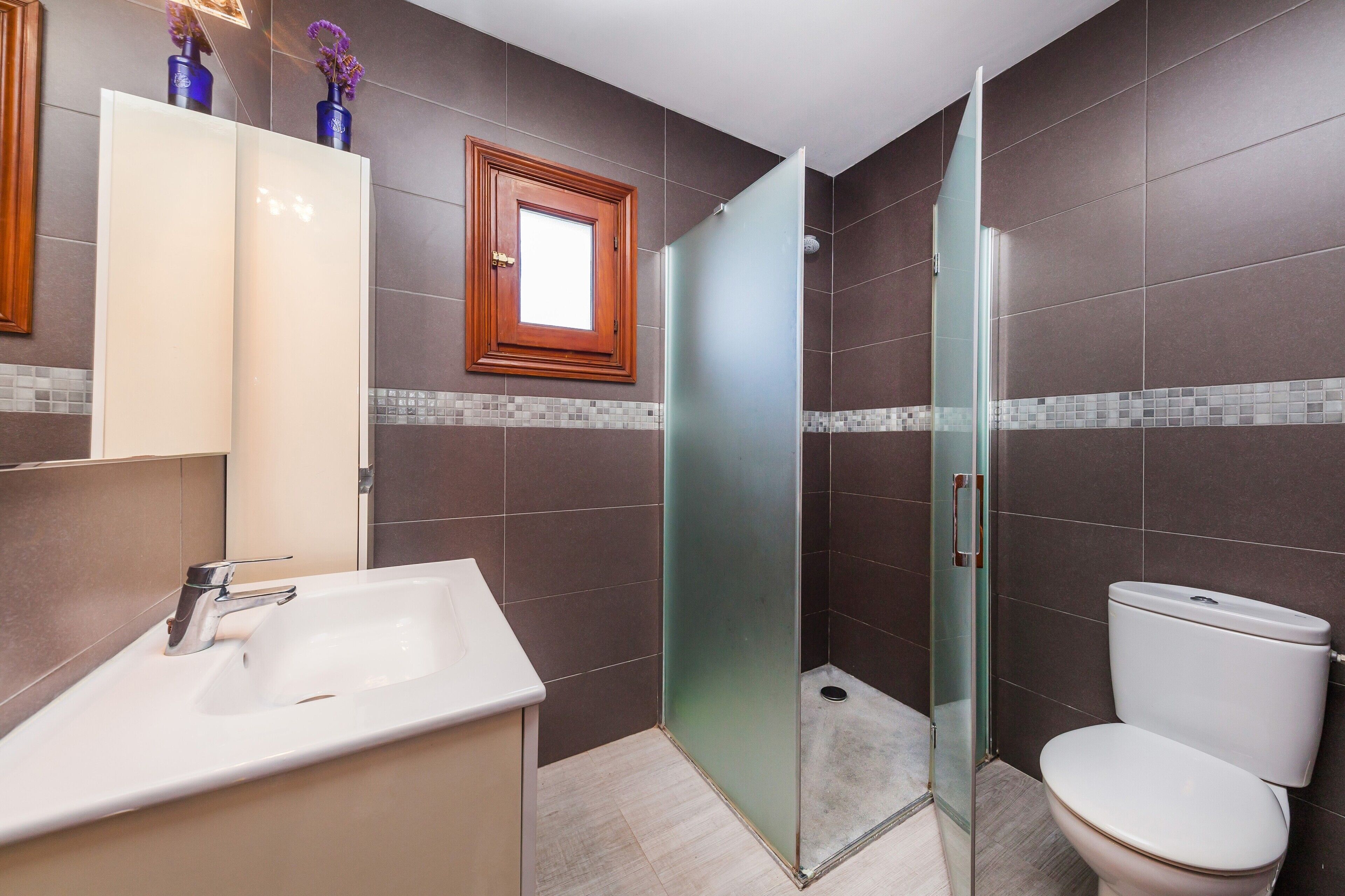 A modern bathroom with a glass-enclosed shower, a white sink, and a toilet.