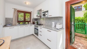 Una cocina moderna con armarios blancos, encimeras de granito, microondas integrado y estufa a gas.