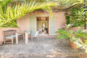 An outdoor patio with a table and chairs, a wooden bench, and a potted plant. - Holiday Home 'Redonda 2' with Mountain View, Shared Pool and Wi-Fi (Costitx)