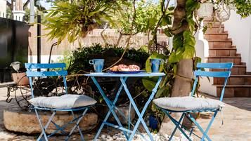 Une table en métal bleue, avec deux chaises, une assiette de nourriture et une plante en pot.