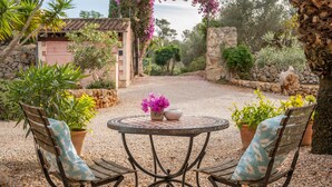 A garden patio with a round table, two chairs, and potted plants. - Holiday Home 'Cascada' with Mountain View, Private Pool and Wi-Fi (Costitx)