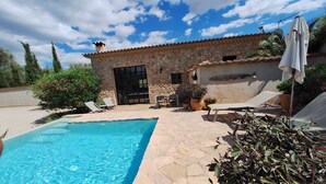 A stone building with a swimming pool, outdoor seating, and potted plants. - Holiday Home 'Cascada' with Mountain View, Private Pool and Wi-Fi (Costitx)