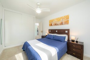 A bedroom with a bed, nightstand, ceiling fan, artwork, and a wardrobe. - Apartamento "La Pergola" with Wi-Fi, A/C, Terrace & Garden (Font de Sa Cala)