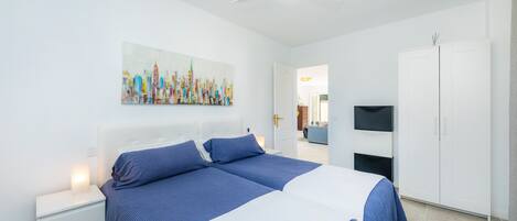 A modern bedroom with a bed, nightstands, a ceiling fan, a TV, and a wardrobe.