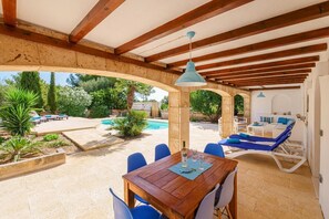 A covered outdoor area with a pool, lounge chairs, and a dining table. - Villa Albatros near the Beach, with Sea View, Garden, Wi-Fi and A/C (Canyamel)