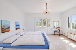 A bedroom with a bed, a desk, a chair, a chandelier, and artwork on the wall. - Villa Albatros near the Beach, with Sea View, Garden, Wi-Fi and A/C (Canyamel)