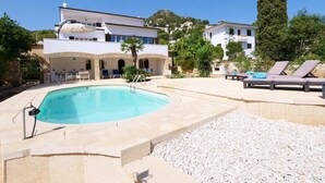 A swimming pool with a sun lounger area, a stone wall, and a building with a tiled roof. - Villa Albatros near the Beach, with Sea View, Garden, Wi-Fi and A/C (Canyamel)