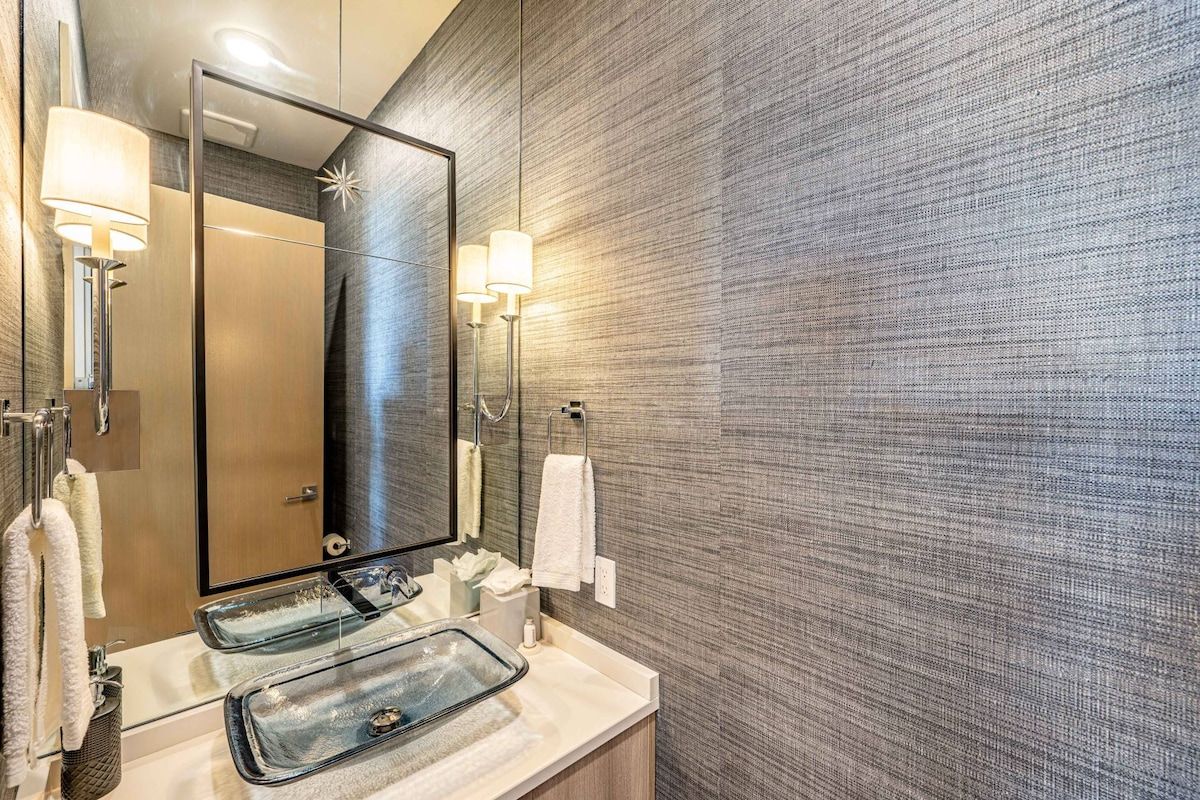 Un baño moderno con un espejo grande, dos lavamanos y toalleros en la pared.
