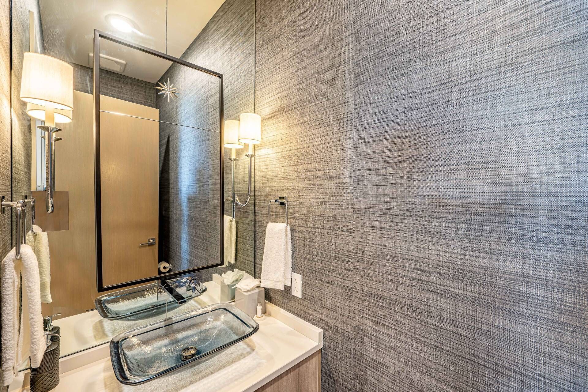 A modern bathroom with a large mirror, two sinks, and towel racks.