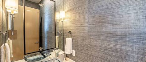 A modern bathroom with a large mirror, two sinks, and towel racks.