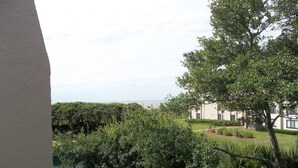 Ein Blick auf ein Gebäude mit einem Wasserelement im Vordergrund, umgeben von üppigem Grün und blauem Himmel.