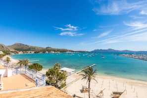 A coastal view with a beach, clear blue water, boats, and mountains in the background. - Holiday Home ‘Apartamento Brisas’ with Sea View, Wi-Fi, A/C & Balcony (Puerto Pollensa)