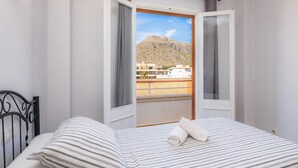 Ein Hotelzimmer mit Bett, einem Fenster mit Bergblick und einem Balkon mit Geländer.