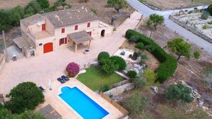 Ein zweistöckiges Haus mit Swimmingpool, überdachter Terrasse und einem gepflegten Garten.
