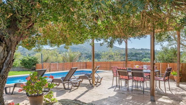 Eine Terrasse mit Pool, Liegestühlen und einem Tisch mit Stühlen.