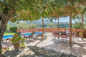 A patio with a pool, lounge chairs, and a table with chairs.