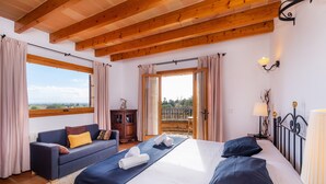 Een slaapkamer met een bed, een bank, een raam en een balkon.