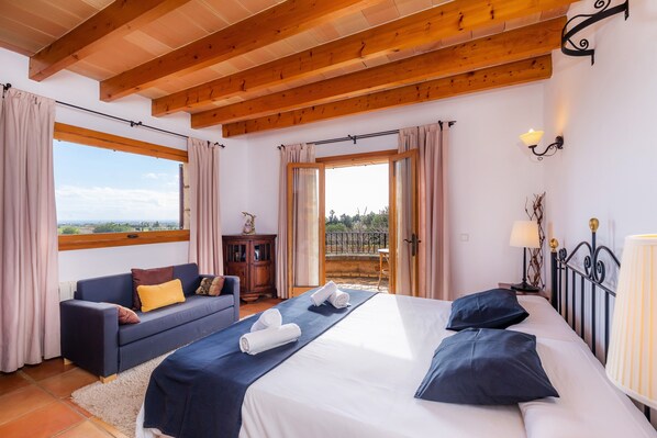 A bedroom with a bed, a sofa, a window, and a balcony. - Country Home Can Bosco with Pool, Wi-Fi, A/C, Garden & Terrace (San Lorenzo de Cardessar)