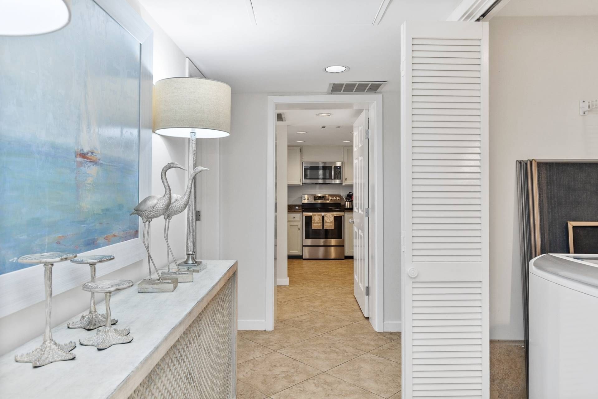 A modern kitchen with stainless steel appliances, a marble countertop, and a view into the dining area.