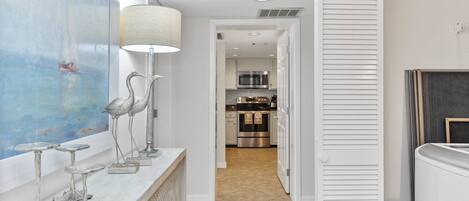 A modern kitchen with stainless steel appliances, a marble countertop, and a view into the dining area.