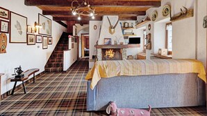 Une pièce comprenant un lit, des poutres en bois, une cheminée et diverses décorations murales.
