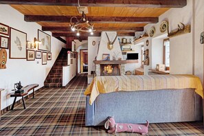 Una habitación con cama, vigas de madera, chimenea y varias decoraciones en las paredes.