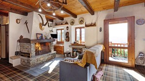Une pièce chaleureuse avec une cheminée en pierre, un plancher à carreaux et un plafond en bois.