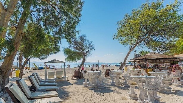 Ein Strandbereich mit Liegestühlen, Korbstühlen und einem Sonnenschirm.