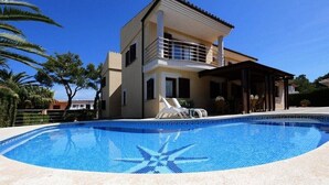 Ein zweistöckiges Haus mit Swimmingpool und überdachter Terrasse.