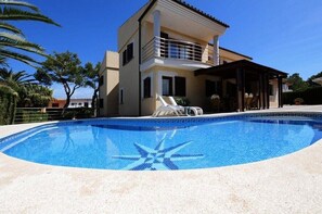 Een tweelaags huis met een zwembad en een overdekte patio.