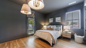 Una camera da letto con un letto grande, due lampade sui comodini, un tavolino, un cesto in vimini e vista dalla finestra.