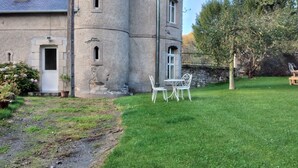 A stone building with a turreted tower, a grassy yard, and a small table with chairs. - Castle outbuilding sleeps 6 (MORLAIX)