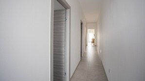 Un pasillo estrecho con una puerta a la izquierda y una ventana al final.