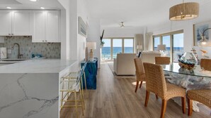 A modern kitchen with white cabinets, a marble countertop, and a view of the ocean. - Gulf Front Condo w/Stunning Views, Private Beach Access, Gulf Front Pool! Tops'l Beach Resort (Miramar Beach)