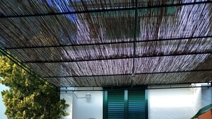 Un patio couvert doté d’un sol carrelé, d’une porte verte et d’un luminaire fixé au mur.