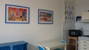 Cozy kitchen area with a white countertop, framed artworks, and a compact dining space.