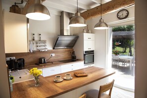 Una cucina moderna con piani di lavoro in legno, lampade a sospensione e vista sull'esterno.