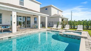 A modern pool area with clear blue water, surrounded by lounge chairs and a covered patio. - Pool /Spa/Games Room/Movie Room/10 mins Disney/Restaurant and Bar/Modern /Chic (Kissimmee)