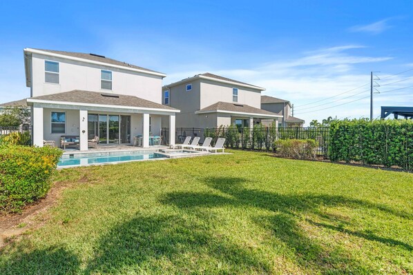 A residential property with a swimming pool, two houses, and a well-maintained lawn.