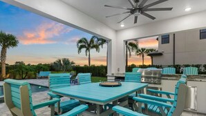 Une terrasse extérieure avec une table et des chaises, un barbecue et une vue sur le coucher du soleil.