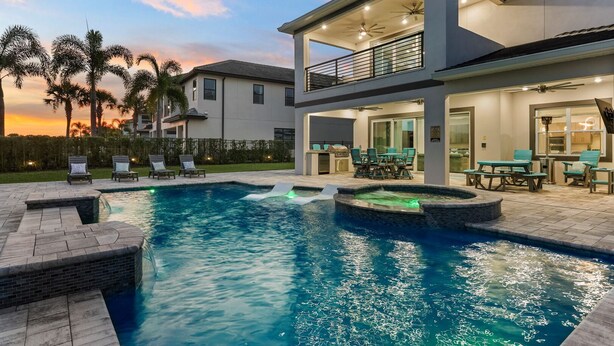 Une maison moderne à deux étages dotée d’une piscine, d’un espace salon extérieur et d’un patio.